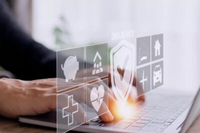 Main d'une personne interagissant avec des icônes d'assurance virtuelles flottantes au-dessus d'un clavier d'ordinateur.