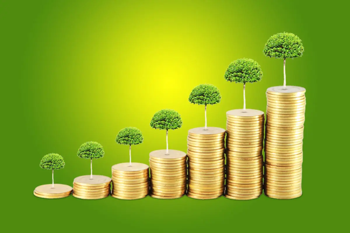 Pièces de monnaie empilées croissantes avec des arbres en sommet sur fond vert, représentant l'investissement dans les obligations vertes.